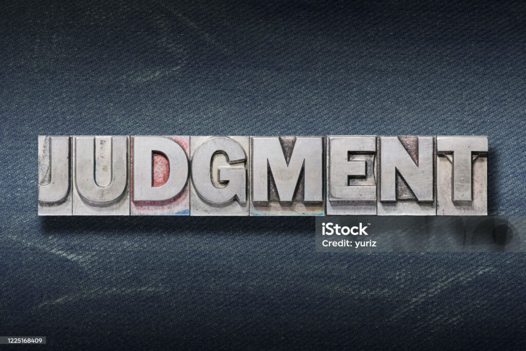 judgment word made from metallic letterpress on dark jeans background