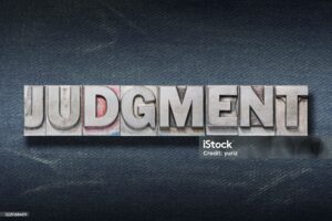 judgment word made from metallic letterpress on dark jeans background